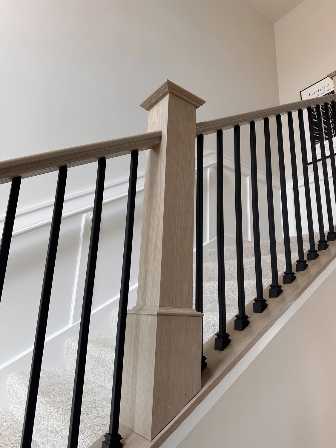 Light wood stair railing with black metal spindles by Bond Trim LLC